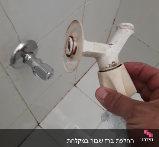 יד מחזיקה ברז ישן עם חלודה